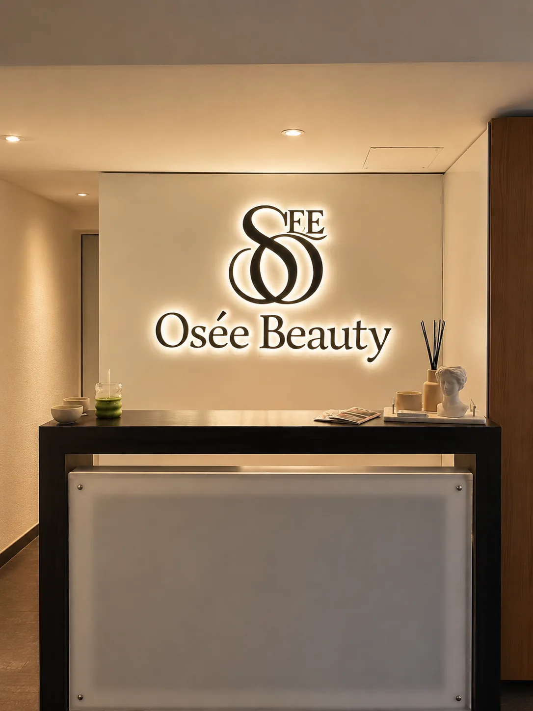 The same reception wall with a warm halo-lit Osée Beauty sign