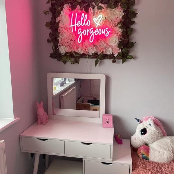 Warm soft pink and golden script LED neon sign glowing softly above a bed in a modern bedroom